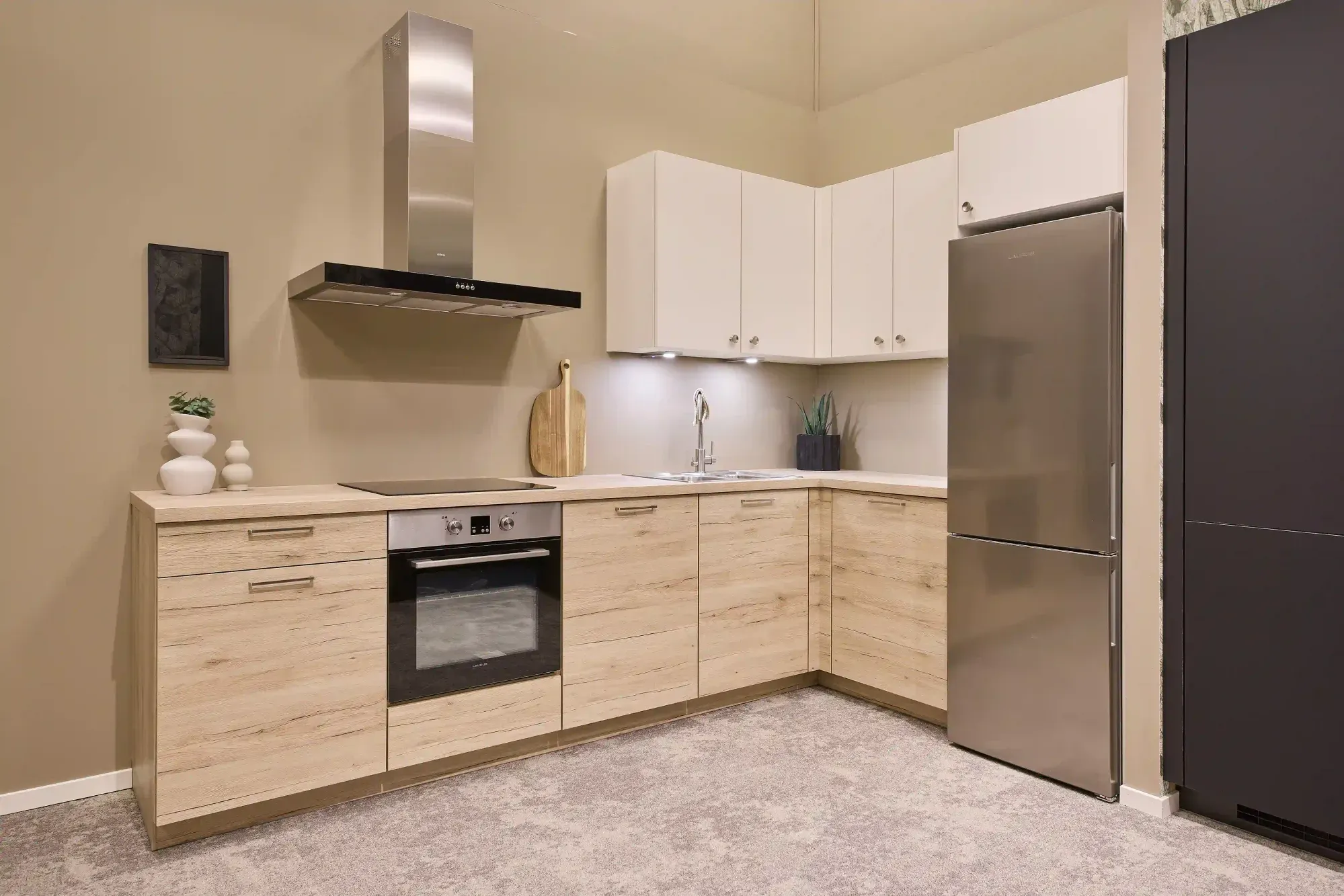 Vaalea puunvärinen keittiö saarekkeella ja kaarihylyllä.